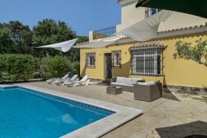 a house with a swimming pool with chairs and an umbrella at Chalet Independiete Con Piscina in Cádiz