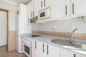 a kitchen with white cabinets and a sink and a microwave at Chalet Independiete Con Piscina in Cádiz