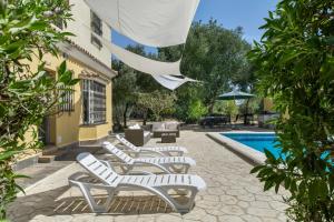 a row of white lounge chairs next to a pool at Chalet Independiete Con Piscina in Cádiz
