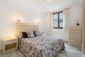 a white bedroom with a bed and a window at Al Mar Los Gigantes in Puerto de Santiago