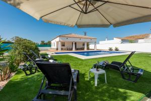 a patio with chairs and an umbrella and a swimming pool at Casa Brisa del Valle in Seville
