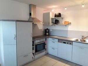 a kitchen with white cabinets and a sink at Ferienwohnung Bieniussa 3 in Gemünden +4 photos