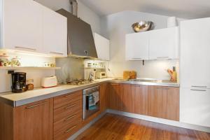 a kitchen with white cabinets and wood floors at Bernhouse in Dorio +18 photos