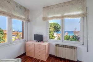 a room with two windows and a television on a dresser at Villa Masnou in El Masnou