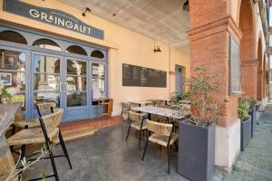 a restaurant with tables and chairs in front of a building at Appartement Graingalet in Carbonne