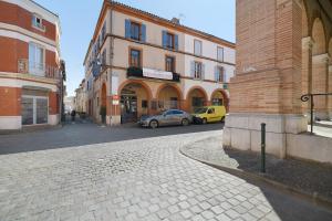 a city street with cars parked in front of buildings at Appartement Graingalet in Carbonne +16 photos