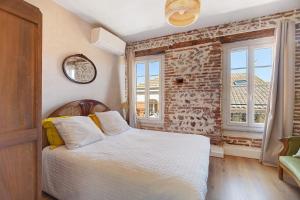 a bedroom with a bed and a brick wall at Appartement Graingalet in Carbonne
