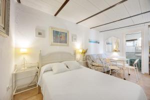 a white bedroom with a bed and a table at La Posada de la Pinaleta in Chiclana de la Frontera