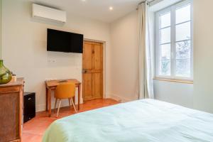 a bedroom with a bed and a desk and a television at Mas Saint Louis in Avignon