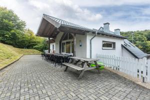 a patio with picnic tables and a white building at Großes Ferienhaus Engelsdorf in Zweifelscheid