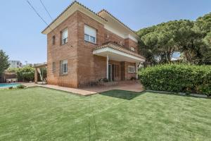 a brick house with a lawn in front of it at Villa Masnou in El Masnou