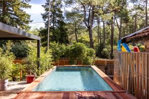a swimming pool in a backyard with a wooden deck at Les Ptis Chiffons in Lacanau