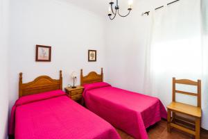 two beds in a room with pink sheets at Chalet Bellavista in Conil de la Frontera