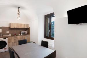 a kitchen with a table and a tv on a wall at Casa vacanza A Cola - con Jacuzzi in Rocchetta Nervina