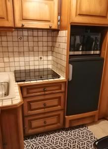 a kitchen with wooden cabinets and a black refrigerator at Maison des Princes de Monaco in Vic-sur-Cère