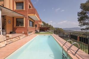 a swimming pool on a deck next to a house at Villa Can Camarassa in Cervelló