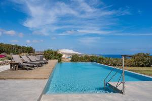 a pool with chairs and the ocean in the background at Luna Rossa Milos - Lavender in Provatas