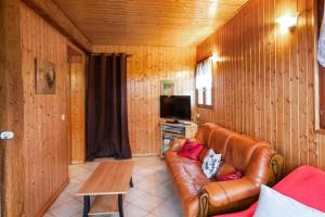 a living room with a leather couch and a tv at Location Vacances Des 4 Vents in Girmont-Val-dʼAjol
