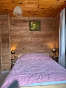 a bedroom with a bed in a wooden wall at Location Vacances Des 4 Vents in Girmont-Val-dʼAjol