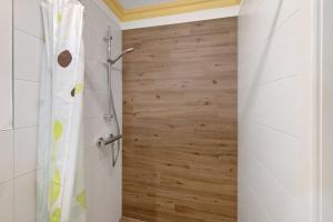 a shower in a bathroom with a wooden wall at Ferienhaus am Rande der Lewitz in Garwitz +16 photos