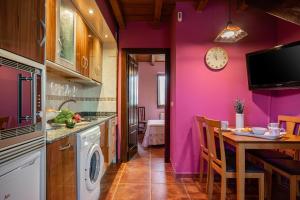 a kitchen with purple walls and a table and a clock at Apto Rosa - Casa el gaitero in Susacasa