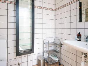 a white tiled bathroom with a sink and a mirror at 2-room apartment in Denmark in Ringkøbing