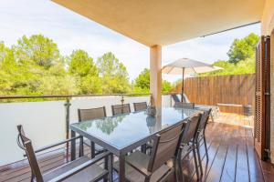 a deck with a glass table and chairs and an umbrella at Tomymar in Cala Ratjada