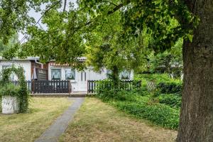 a white house with a tree and a sidewalk at Bungalow 91 in Zeulenroda
