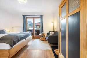 a bedroom with a bed and a chair and a window at Fewo Am Steinbach - Lofer in Reit im Winkl