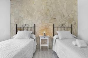 two beds in a bedroom with a stone wall at Casa Faquinse La Muela 1 in Vejer de la Frontera +18 photos