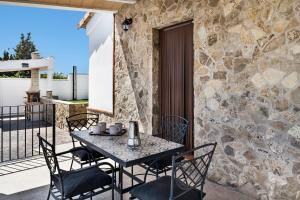 a table and chairs on a patio with a stone wall at Casa Faquinse La Muela 1 in Vejer de la Frontera