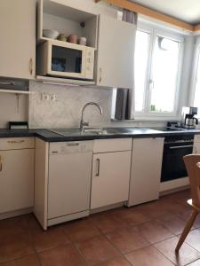 a kitchen with white cabinets and a sink and a microwave at Appartment Isabelle Home in Hermagor
