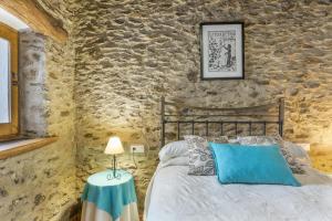 a bedroom with a bed and a stone wall at Casa El Portón, Bubión in Bubión