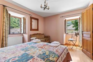 a bedroom with a bed and a chair and two windows at Puente del Narcea 1 in Cibuyo