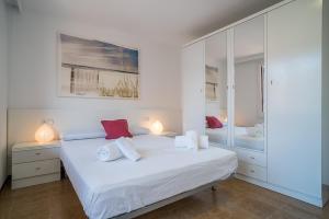a white bedroom with a bed and a mirror at Canet beach 3 in Canet de Mar
