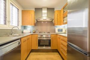 a kitchen with wooden cabinets and a stainless steel refrigerator at Canet beach 3 in Canet de Mar +11 photos