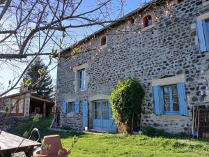 a stone house with blue doors and a yard at La Garnasette in Beaulieu