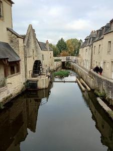 a canal in the middle of a city with buildings at Le Royal in Bayeux