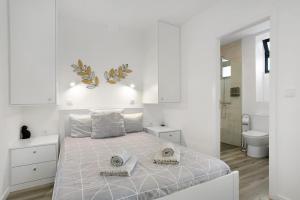 a white bedroom with a large bed and a bathroom at Casa Pereira in Ponta do Pargo