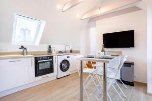 a kitchen with a table and a tv on a wall at Ty Sterenn - 400m de la plage in Le Guilvinec