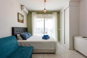 a bedroom with a bed and a couch and a window at Plata Centro in Torremolinos