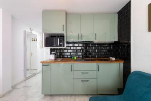 a kitchen with white cabinets and a black tile wall at Plata Centro in Torremolinos