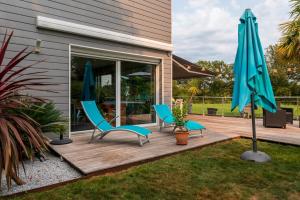 two blue chairs and an umbrella on a deck at Côté Vannes in Ploeren