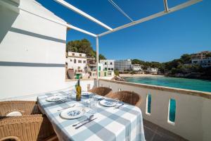 a table on a balcony with a view of the water at Sa Barca - Can Ferrando in Cala Santanyi +8 photos