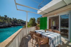 a table on a balcony with a view of the water at Sa Barca - Can Ferrando in Cala Santanyi