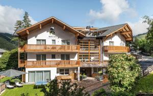 a large white building with a wooden roof at Apartment Ön Residence Bun Ste in San Vigilio Di Marebbe