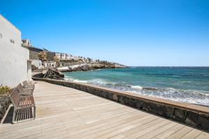 a bench on a boardwalk next to the ocean at Apartamento Porís in Arico