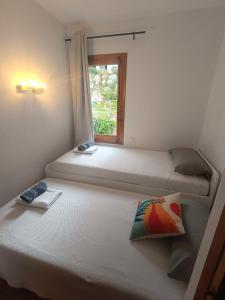 two beds in a room with a window at Costa Arenal - Biniplaya in Arenal d'en Castell +18 photos