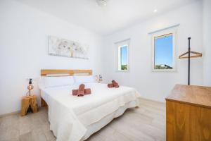a white bedroom with a bed and two windows at Son Crespi Vell 2 in Manacor