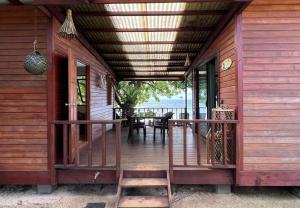 a porch of a wooden house with a table and chairs at Tahiti Sunrise Beach in Vaitoare